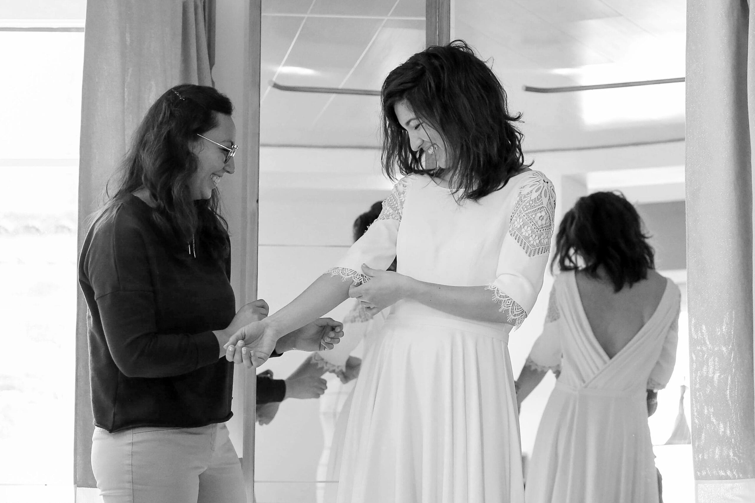 Photo d'essayage de robe de mariée sur-mesure, menant aux finitions et ajustement de la création : dernière retouche avant livraison de la pièce unique