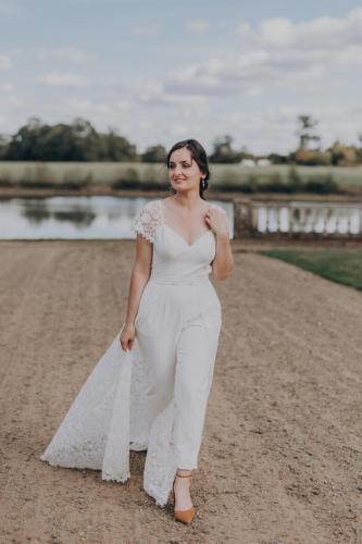 Une combinaison de mariée chic et intemporelle, avec une traîne en dentelle amovible pour un effet spectaculaire.