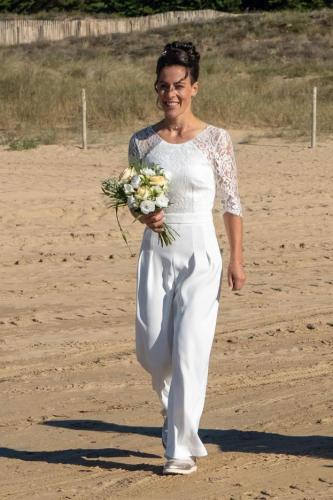 Une combinaison de mariée moderne et élégante, sublimée par des manches en dentelle délicate, pour une silhouette à la fois chic et romantique.