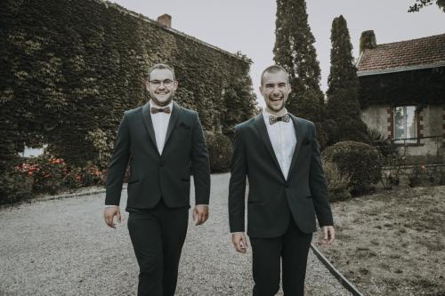 Des costumes bleu nuit pour témoins, élégamment rehaussés d’un col châle noir, dans le style d’un smoking classique pour une allure chic et intemporelle.