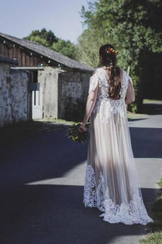 Une robe de mariée bohème, alliant le blanc et le beige, avec des détails fluides et des touches de dentelle pour une allure libre et pleine de charme.