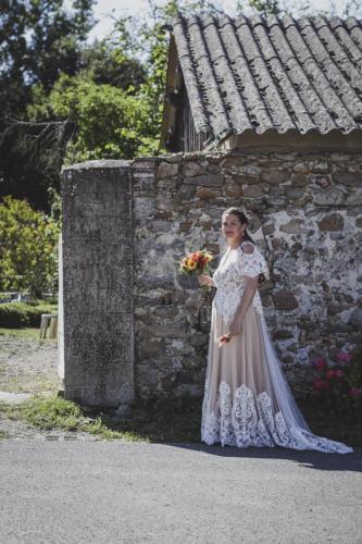 Une robe de mariée bohème, alliant le blanc et le beige, avec des détails fluides et des touches de dentelle pour une allure libre et pleine de charme.