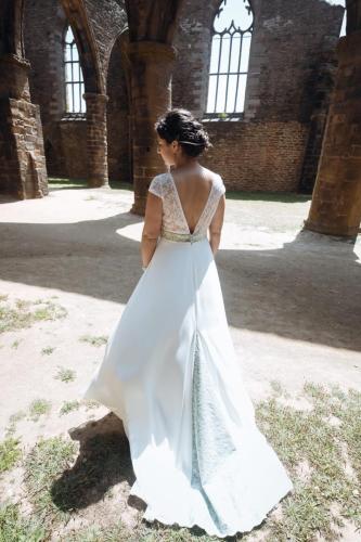 Une robe de mariée romantique, ornée de dentelle à petites fleurs, avec une quille délicatement colorée de vert d'eau pour un effet frais et poétique.