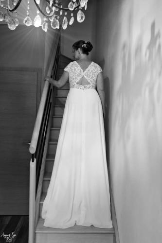 Une robe de mariée fluide et élégante, avec un haut délicatement orné de dentelle, créant une silhouette gracieux et raffinée.