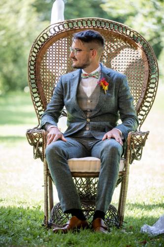 Un costume bleu chiné élégant, associé à un gilet à carreaux gris pour un look moderne et sophistiqué, alliant textures et couleurs subtiles.