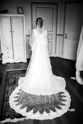Une robe de mariée gracieuse, accentuée par des manches transparentes et un immense voile, pour une allure royale et éthérée, créant un effet spectaculaire à chaque mouvement.
